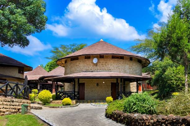 A beautiful circular stone building with a thatched roof surrounded by lush greenery under a clear blue sky.